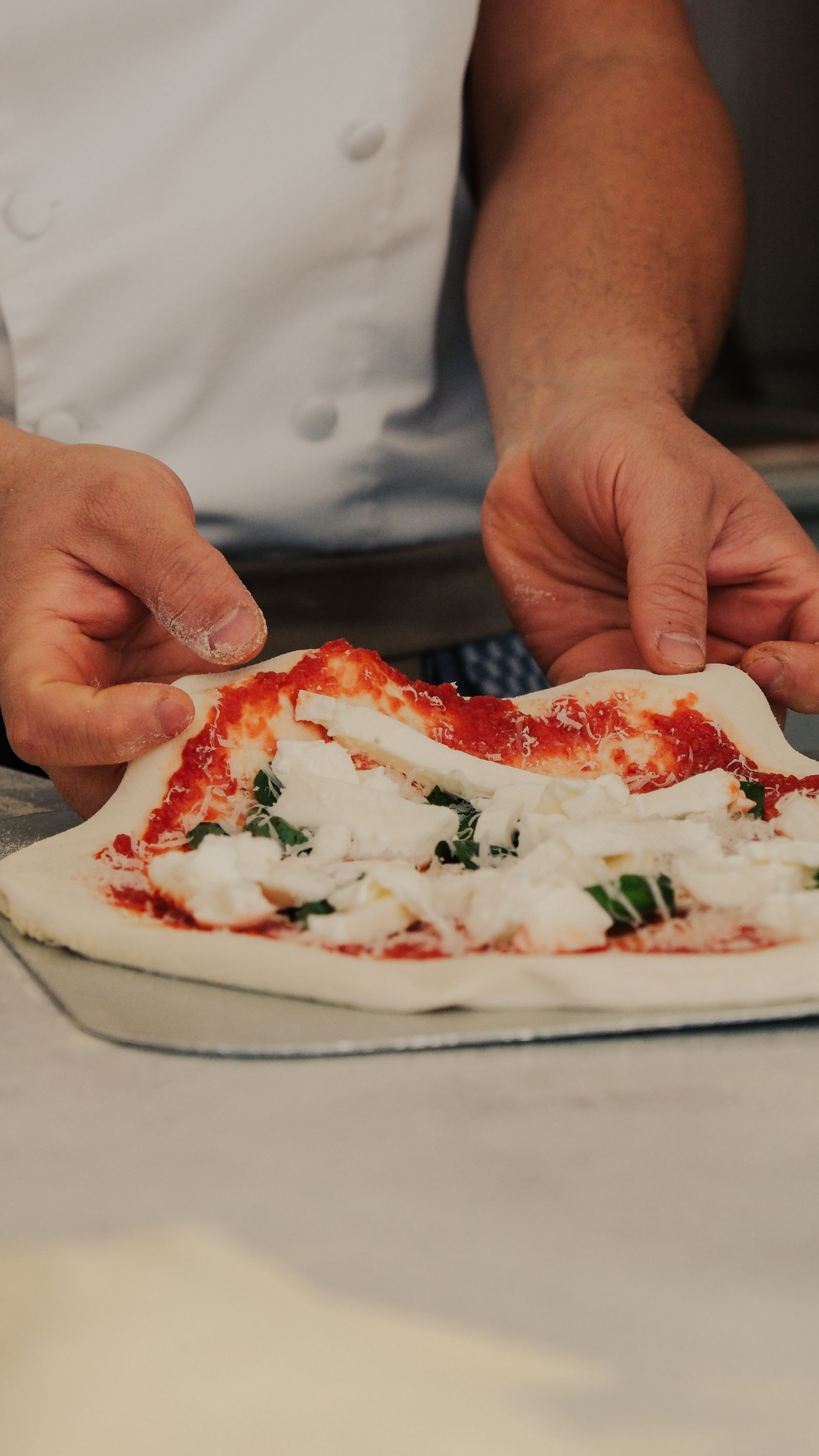 Koki menambahkan bahan segar ke pizza